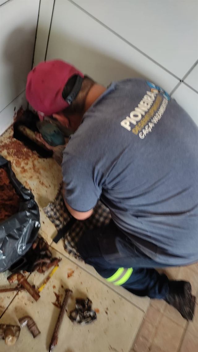 Técnico trocando tubulação antiga no piso de um banheiro